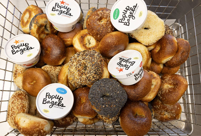 Assorted PopUp Bagels with cream cheese containers in a metal basket